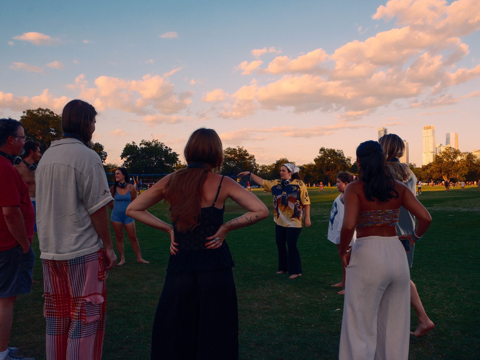 Crowd dancing under pink sunset clouds in an Austin park