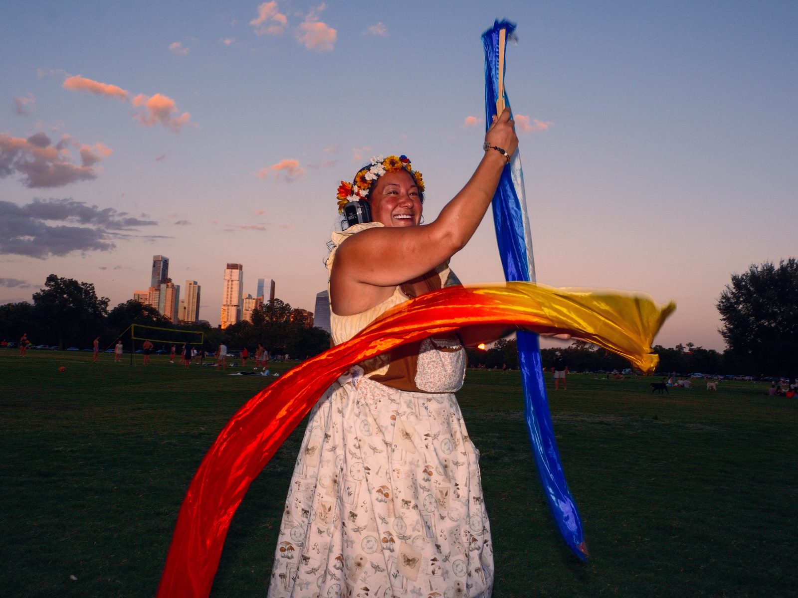 Dancer twirling a rainbow silk scarf at a park silent disco